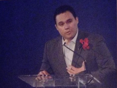 Gerardo reading poetry at a glass podium